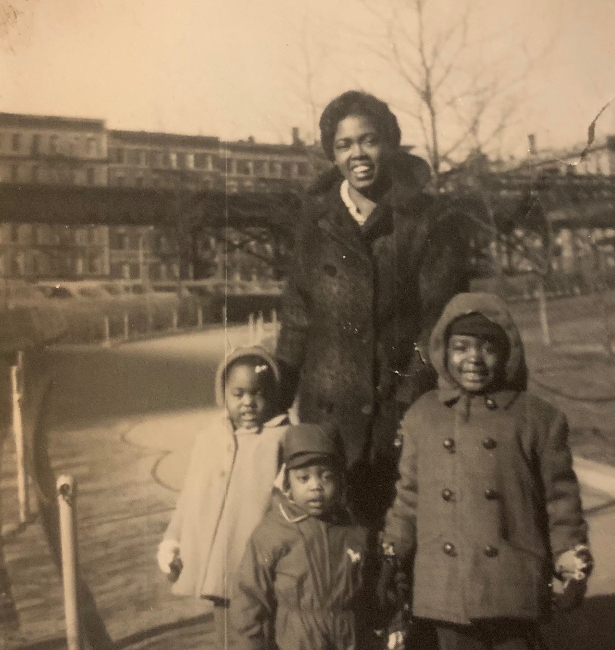A mother and three children bundled in winter coats in a city park, January 1962