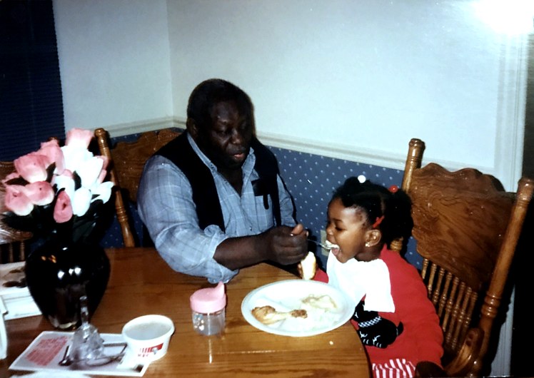 Sylvester feeding his granddaughter at the kitchen table