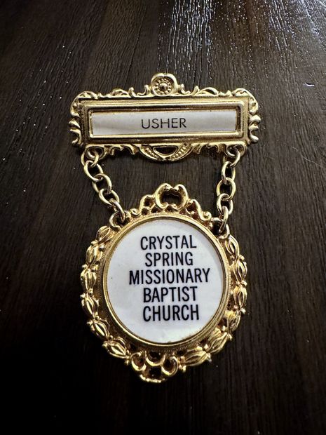 A gold church usher pin from Crystal Spring Missionary Baptist Church